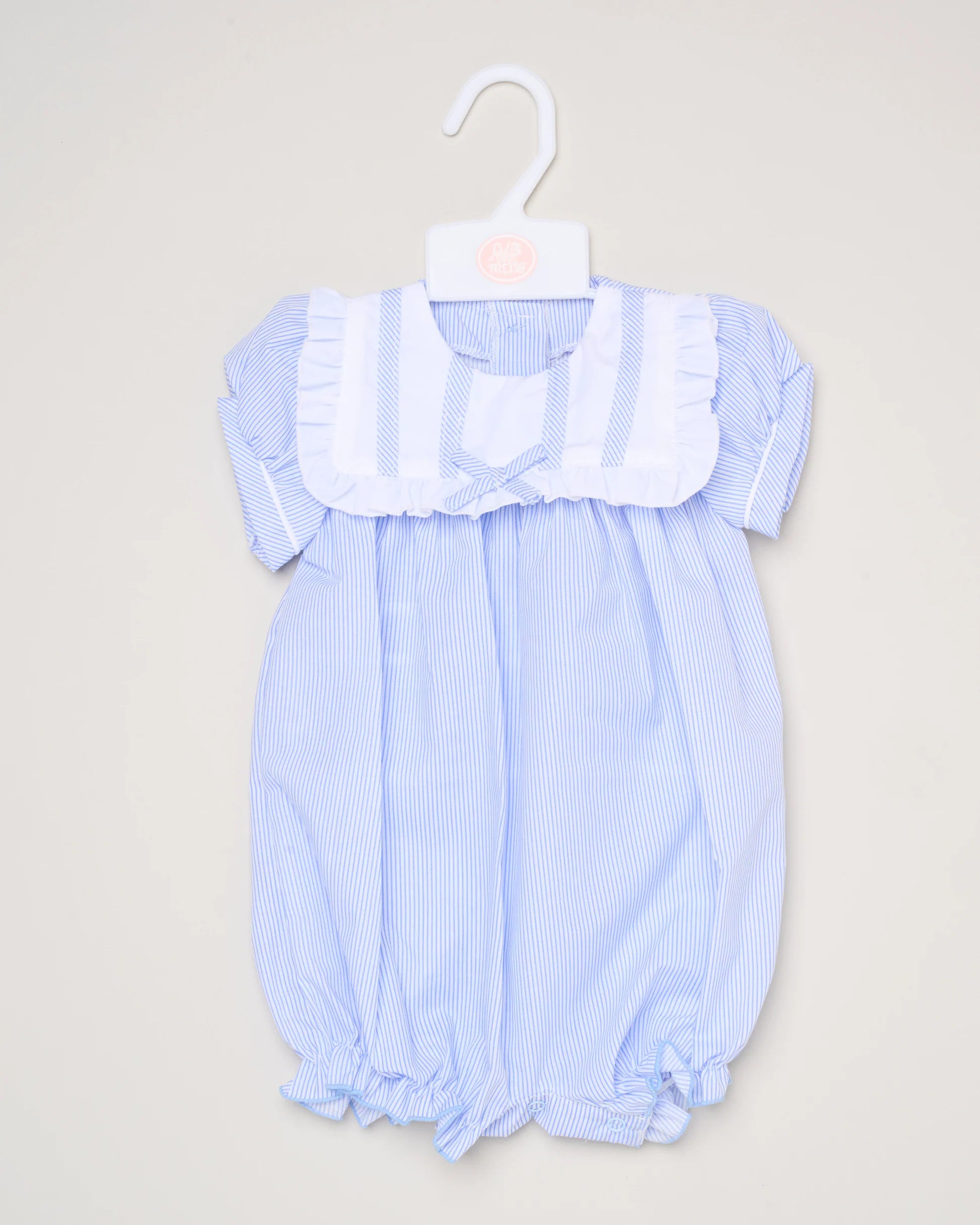 The Baby Girls Smocked Romper features light blue and white stripes, short puffed sleeves, a white ruffled bib collar, and gathered leg openings. It's shown on a white hanger against a plain background.
